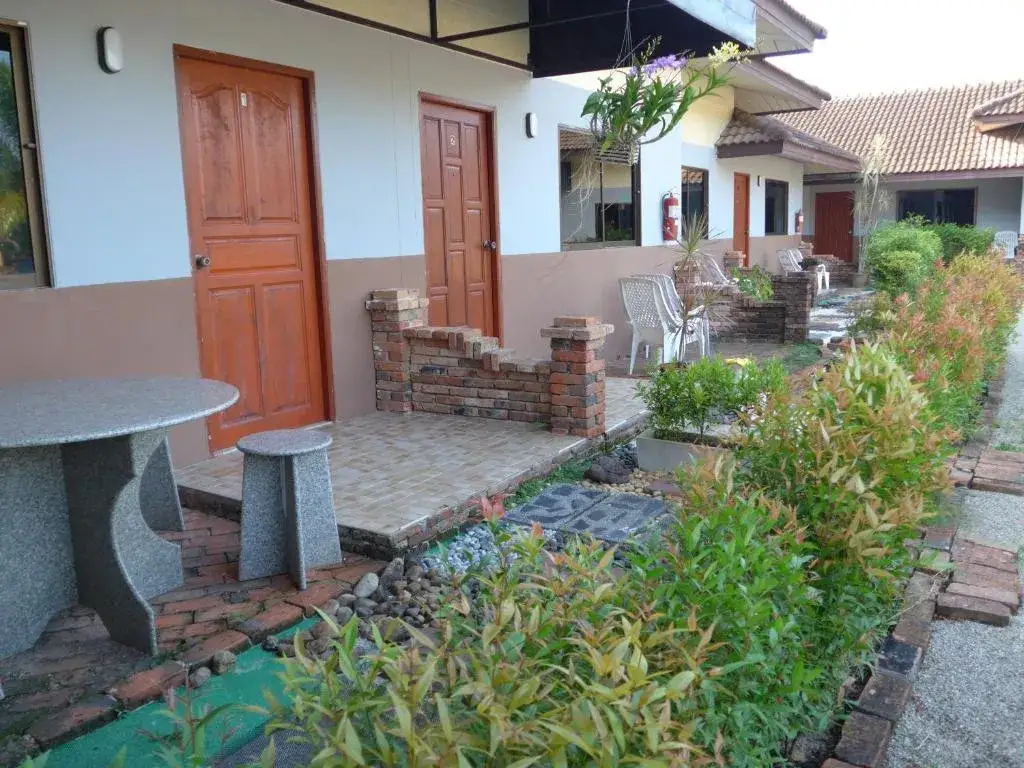 Walkway along the bungalow-style building at Forum House Hotel Krabi with gardens and wooden doors