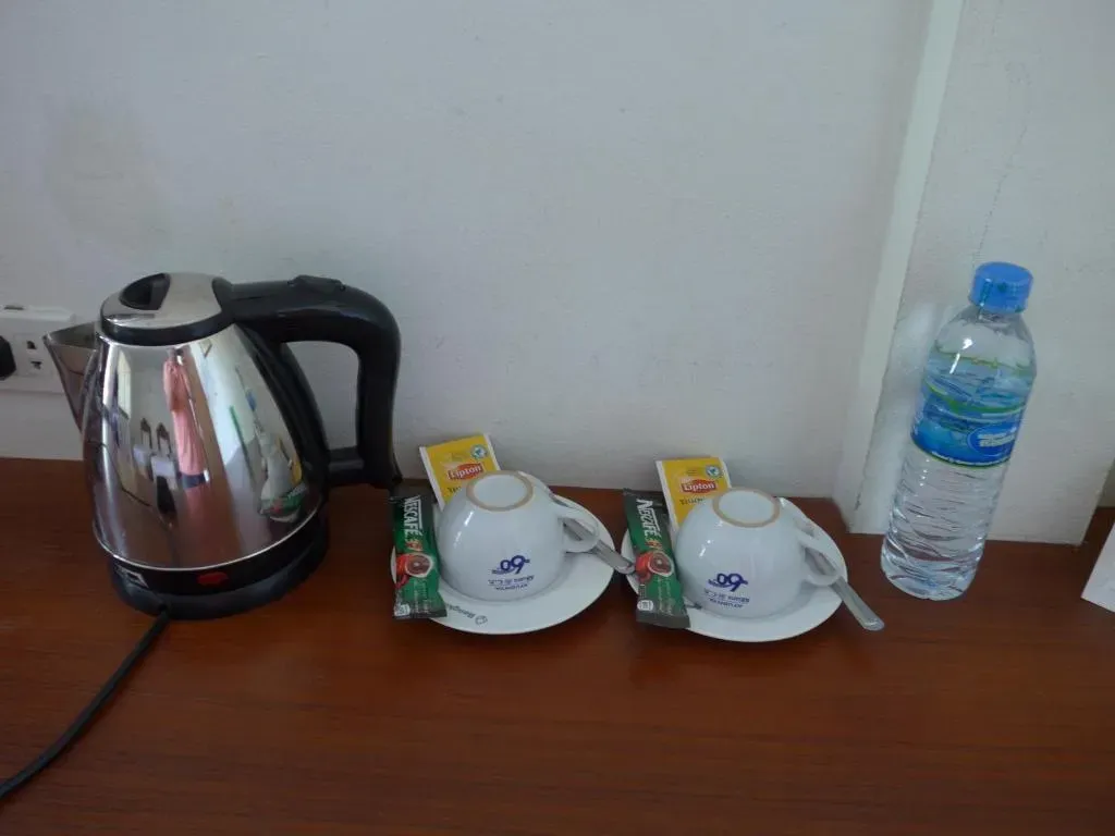 Tea and coffee making facilities on a desk in a guest room, including kettle, cups, and bottled water